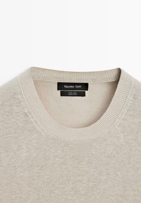 Beige linnedragt med rund hals og ribbet krave samt sort label med teksten "Massimo Dutti, 100% hør, lavet i Kina."