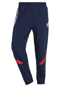 Pantalones deportivos navy con acentos en blanco y rojo, que cuentan con una cinturilla elástica, piernas ajustadas y rayas laterales. Fabricados con material ligero.