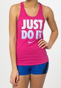 Růžový bezrukávový tank top Nike s bílým textem "JUST DO IT" v modrém přechodu; v kombinaci s modrými šortkami s černými akcenty.
