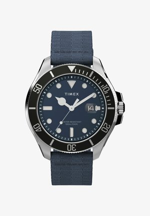 Ceas Timex cu carcasă din oțel inoxidabil, brățară din material textil bleumarin, bezel negru și cadran rotund albastru. Rezistent la apă până la 100m/330ft.