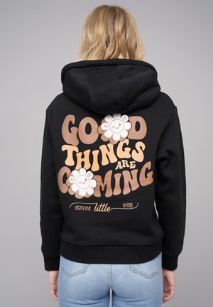 Black hoodie featuring a large graphic on the back with text reading "Good Things Are Coming," accompanied by two flower designs.