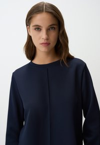 Felpa blu navy con collo rotondo, tessuto testurizzato e discreti dettagli delle cuciture sul davanti, con maniche lunghe e un fit rilassato.