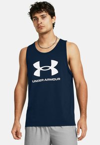 Tengerészkék ujjatlan póló, puha anyagból készült, elől nagy fehér Under Armour logóval. Ujjatlan kivitel és laza fazon.