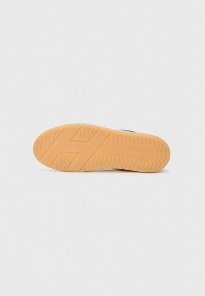Gummisåle med et bølge mønster, som har en beige farge og en logo. Bunnsynsvinkel viser et sporty, holdbart design.