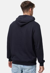 Marineblauwe hoodie met een trekkoordcapuchon, lange mouwen en ribgebreide manchetten en hem. Gemaakt van zachte stof met een gladde textuur.