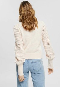 Pull en tricot rose clair avec des rayures verticales texturées et des détails en ajouré sur les manches, avec des poignets et un ourlet côtelés. Coupe décontractée.