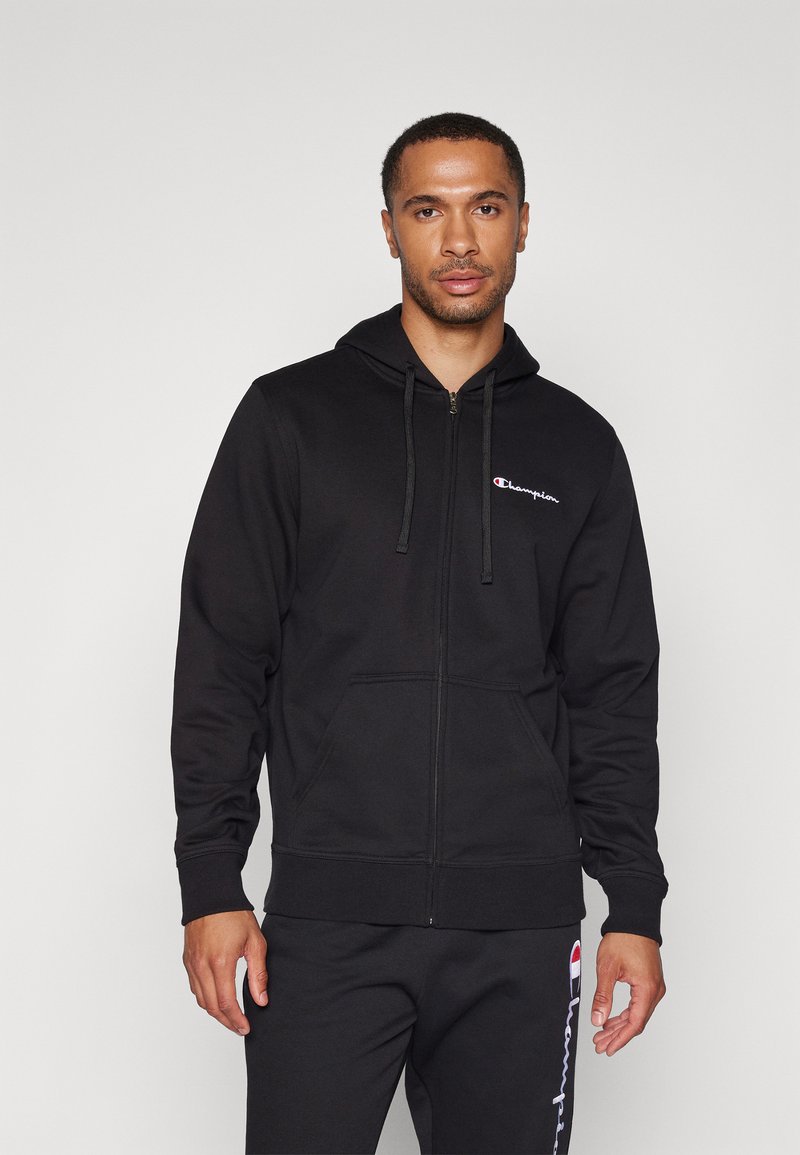 Schwarze Reißverschluss-Hoodie aus Baumwollmischung, mit verstellbarem Kordelzug an der Kapuze, Fronttaschen und gesticktem Logo auf der linken Brust.