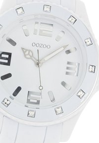 White silicone watch with a round face, silver-tone hardware, large numerals, and crystal accents at each hour marker.