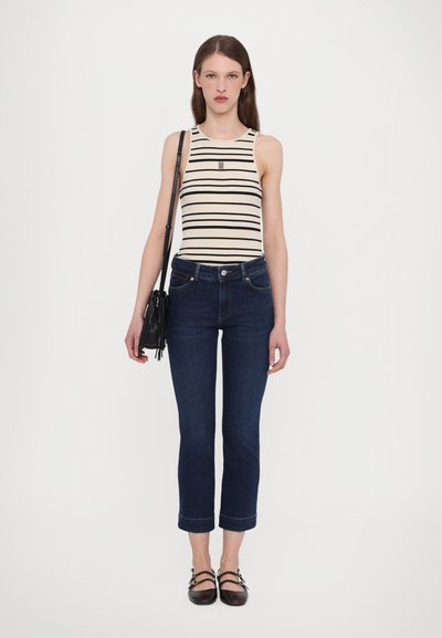 Wit en zwart gestreept tanktop, donkerdenim cropped jeans, zwarte handtas en zwarte platte schoenen met bandjes.