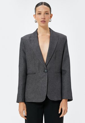 Donkergrijze blazer met een gestructureerd ontwerp, enkele knoopsluiting en scherpe revers. Bevat twee voorzakken en een soepele, textuurrijke stof.