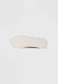 Σόλα μαύρου αθλητικού παπουτσιού με λευκή εξωτερική σόλα από καουτσούκ με μοτίβο διαμαντιού και το λογότυπο "Tommy Jeans" στο κέντρο.