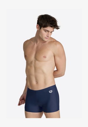 Shorts de bain navy en tissu lisse et extensible, avec un accent logo à l'avant et un design ajusté pour un maintien sécurisé.