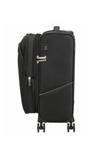 Valise souple noire à coque souple avec quatre roues, double curseur de fermeture éclair verrouillé par une serrure TSA intégrée à combinaison, et une poche latérale extensible.