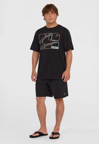 Sort T-shirt med multicolor geometrisk grafik, parret med sorte shorts og flip-flops, lavet af letvægtsstof.