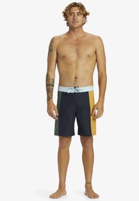 Herren-Badehose mit mehrfarbigem Design: marineblau, türkis, gelb und hellblau. Verfügt über einen verstellbaren Bund und einen mittellangen Schnitt.