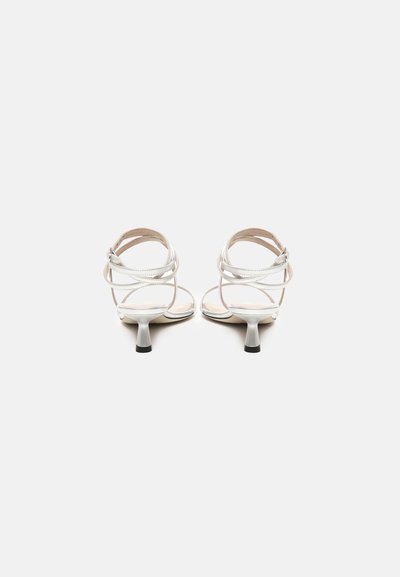 Sandalias blancas con tiras y tacón delgado, que muestran una textura suave y un diseño minimalista. Correa de tobillo ajustable para un mejor ajuste.