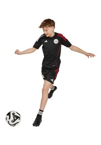 Svart fotbollströja och shorts med röda accenter, logotyp på bröstet och tre ränder på ärmarna. Svarta fotbollsskor och en svart-vit fotboll.