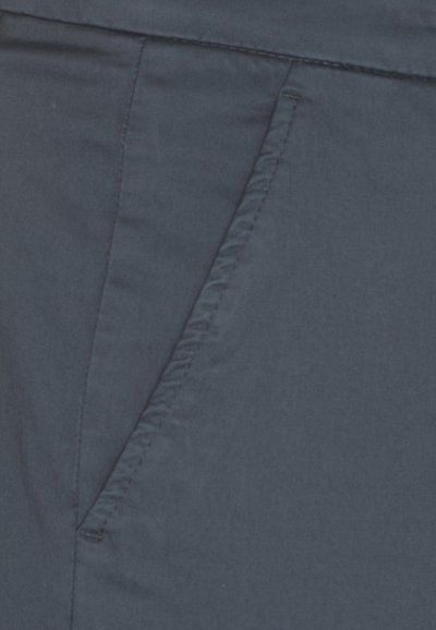 Tessuto blu navy, con una tasca laterale caratterizzata da una cucitura pulita. Il materiale appare liscio con una leggera lucentezza, indicando una texture leggera.