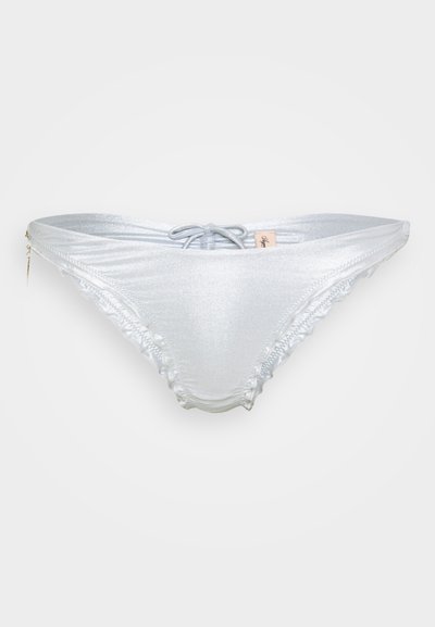 Mirdzošas sudraba bikini apakšda ar priekšējo saitīti un viļņota mala, attēlota uz vienkārša balta fona.