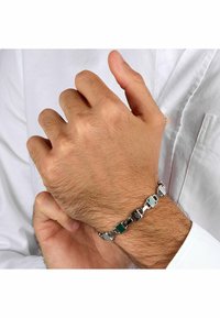Zilverkleurige armband met rechthoekige schakels en groene emaille accenten. Fijne textuur met een gepolijste afwerking, gedragen om een pols.