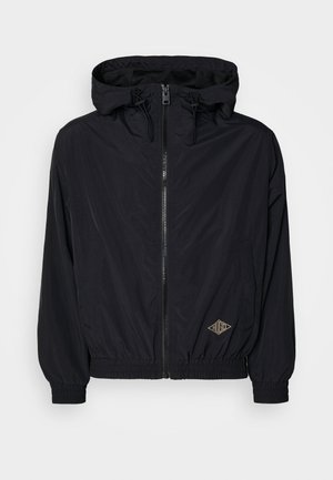 Black lightweight jacket with a hood, zip closure, elastic cuffs, and hem. Features a small logo in gold on the front right side.