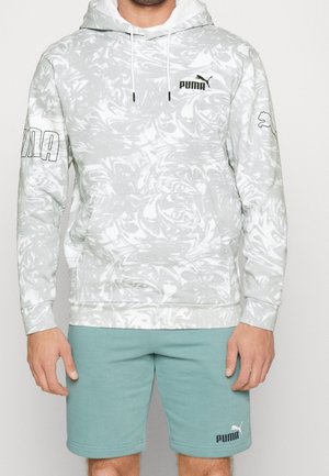 Homme portant un sweat à capuche Puma marbré blanc et gris avec un logo sur la poitrine et les manches, associé à un short Puma bleu sarcelle avec un logo sur la jambe gauche.