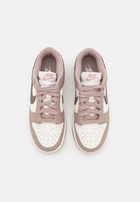Pair of white and dusty pink Nike sneakers with laces, viewed from above on a plain light background.