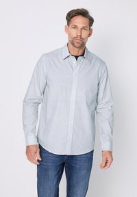 Herenoverhemd met knopen in een lichtblauw-wit ruitpatroon. Voorzien van een klassieke kraag, lange mouwen en een afgeronde zoom. Draagt goed bij een blauwe spijkerbroek.