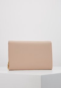 Béžové kožené psaníčko s hladkým povrchem, přehnutým klopou a zlatým řetízkovým řemínkem. Vyznačuje se čistými liniemi a minimalistickým designem.