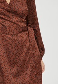 Vestido envolvente marrón de tela suave, con un estampado de leopardo negro, mangas largas y un detalle de cintura atada.