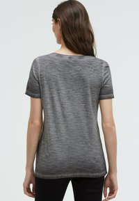 Gray, short-sleeve t-shirt with a soft texture and a slightly relaxed fit. Back view shows a subtle heather pattern and scoop neckline.