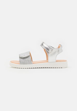 Silver sandal with a glittery upper and metallic accents. Features adjustable straps and a textured white sole for grip. Lightweight design.