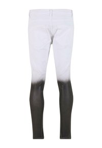 Slim fit džíny s bílou horní polovinou, která přechází do jednobarevné černé od kolen dolů, zobrazené zezadu s viditelnými kapsami.