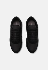 Zwarte sportieve schoenen met een soepel synthetisch bovenwerk, textuuraccenten en vetersluiting. Gevoerde binnenzolen en rubberen zolen zorgen voor comfort.