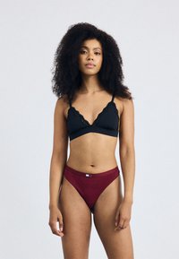 Mustat pitsireunaiset bralette ja viininpunaiset hipster-pikkarit. Pehmeää kangasta, kolmio-muotoinen bralette ja merkkiväri vyötäröllä pikkareissa.