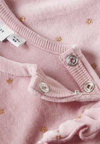 Tessuto rosa chiaro con trama fine, decorato con motivi di stelle dorate metalliche. Comprende chiusure a scatto e un colletto a coste per una facile vestibilità.