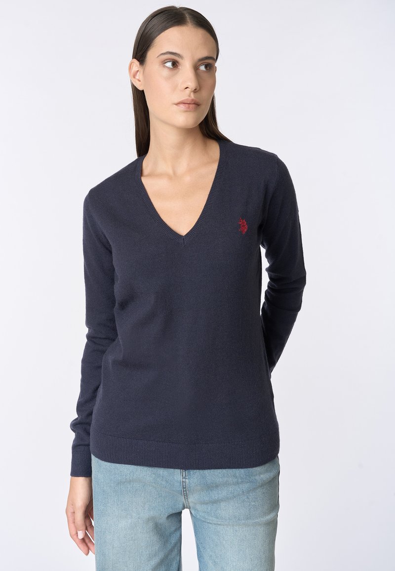 Maglione a V navy, realizzato in morbido tessuto a maglia, con maniche lunghe e un piccolo logo rosso accento sul lato sinistro del petto.
