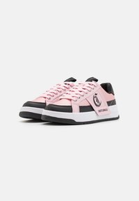 Rosa och svart sneaker med en slät syntetisk ovandel, rund tå, platta snören, gummisula och logotypdetalj på sidan.