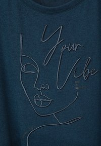 Mörk teal T-shirt med broderade linjer som formar ett ansikte och texten "Your Vibe." Mjuk textur med rundad halsringning.