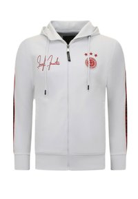 Witte zip-up hoodie met een fitted ontwerp. Heeft rode accenten, een capuchon, sterren en branding op de borst en mouwen. Zachte stoftextuur.