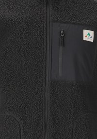 Gilet en polaire noir avec une poche poitrine zippée dotée d'un panneau en tissu, des poches latérales et une pièce de logo avec des éléments de design géométriques.