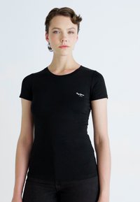 Tricou negru, ajustat, cu mâneci scurte, realizat dintr-un material moale. Are un mic logo pe partea stângă a pieptului. Design simplu cu guler rotund.