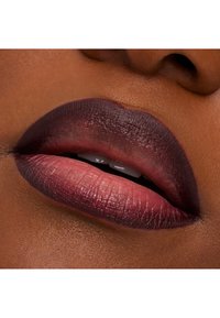 Nærbilde av lepper som viser en gradientfarge fra dyp plomme til myk rose, med en jevn tekstur og synlige fine linjer. Subtil glans er tydelig.