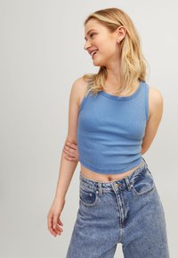 Top cropped azul claro com nervuras e decote redondo, combinado com jeans de ganga azul claro de cintura alta. Textura suave, design justo.