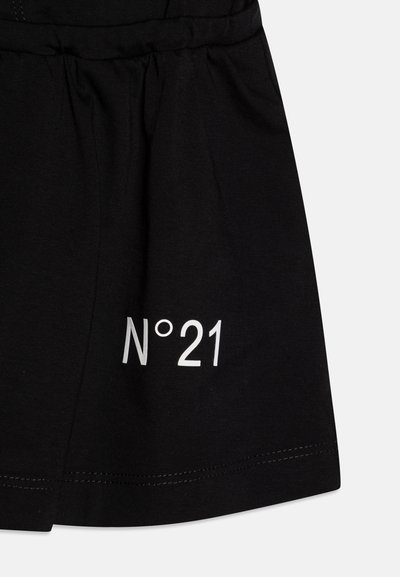 Svart bomullskjol med rynkad tyg, resårmidja och en framträdande vit tryckt "N°21" etikett på framsidan.