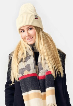 Cremfarbener, gerippter Strickmütze mit einem kleinen Logopatch, kombiniert mit einem gemusterten Schal in den Farbtönen Beige, Schwarz, Rot und Grau.