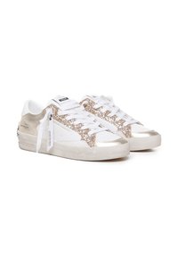 Sneakers bianchi con accenti dorati luccicanti, materiale testurizzato, suole piatte e lacci robusti. Dettagli lucidi in oro sulla punta e sul tallone.