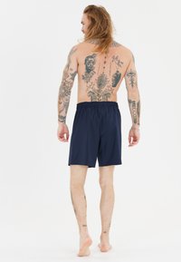 Siniset uimapöksyt, jotka on valmistettu kevyestä kankaasta. Elastinen vyötärö ja yksinkertainen muotoilu ilman näkyviä logoja tai kuvioita.