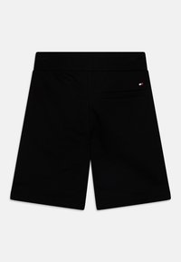 Shorts noirs en tissu lisse, avec une taille élastique et une poche arrière unique avec un petit logo.