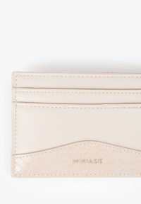 Porta carte in pelle beige con un accento testurizzato alla base. Dotato di quattro scomparti per carte e logo "MIRIADA" impresso a rilievo.